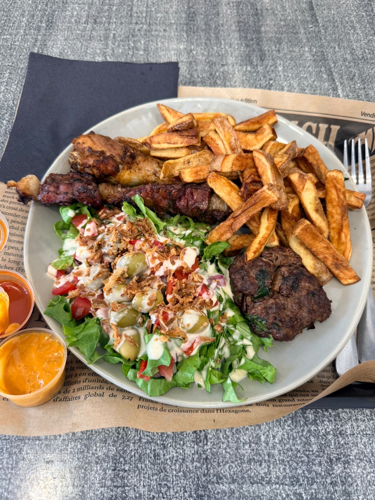 Assiette cuisse de poulet grillée, brochette de viande, steak haché, frites maison et salade aux olives
